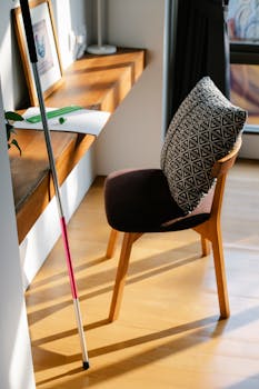Modern home office setup with wooden furniture, cozy chair, and natural sunlight streaming in.