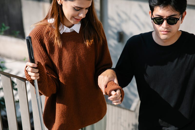 Support worker guiding a visually impaired woman along a pathway outdoors