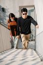Photo of Woman Assisting Man to Walk Up the Stairs