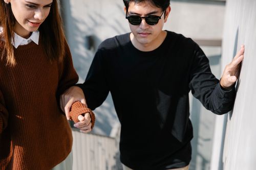 Free Man with sunglasses receiving help from a woman outdoors in daylight. Stock Photo