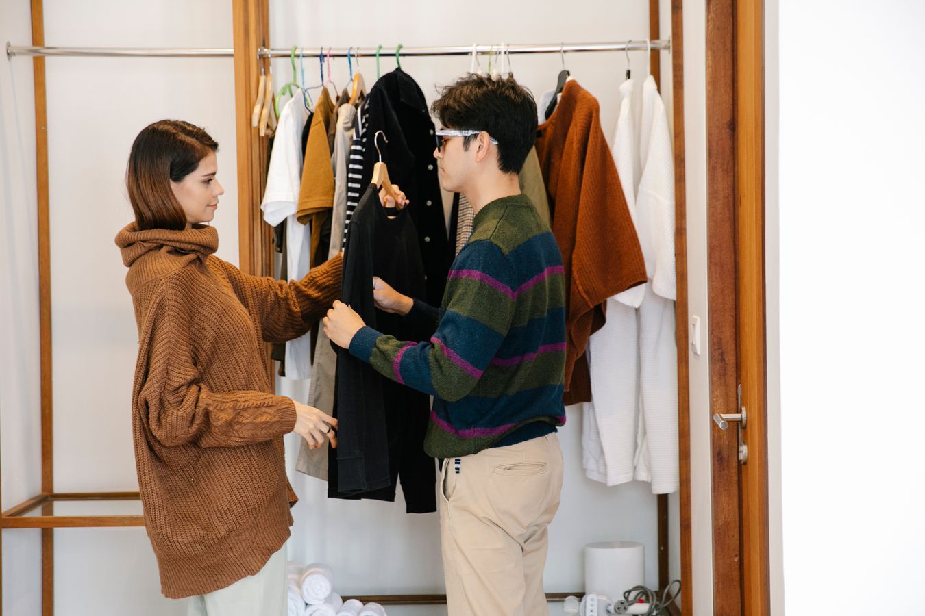 Person selecting folded clothing from a closet shelf