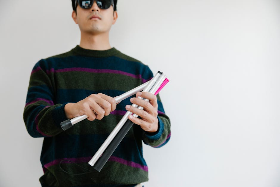 Man wearing sunglasses assembling a walking cane, symbolizing support for visual impairment.