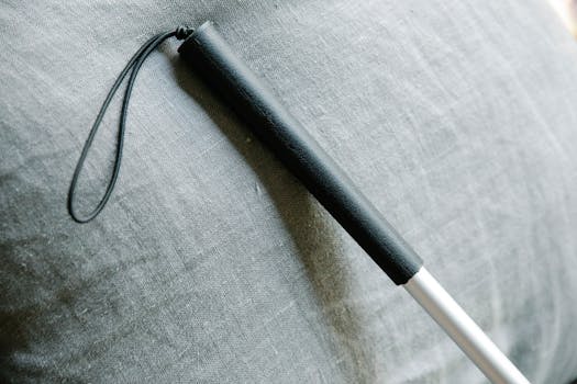 Detailed view of a white cane against a textured fabric background, symbolizing support for the visually impaired.