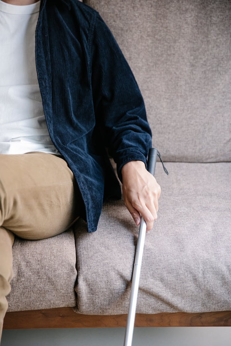 Photo Of Person Sitting On Couch While Holding Walking Stick 