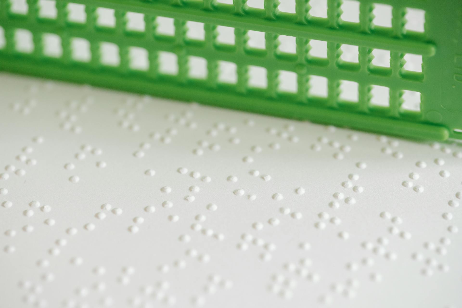 Detailed image of braille dots on textured paper featuring a green grid ruler.