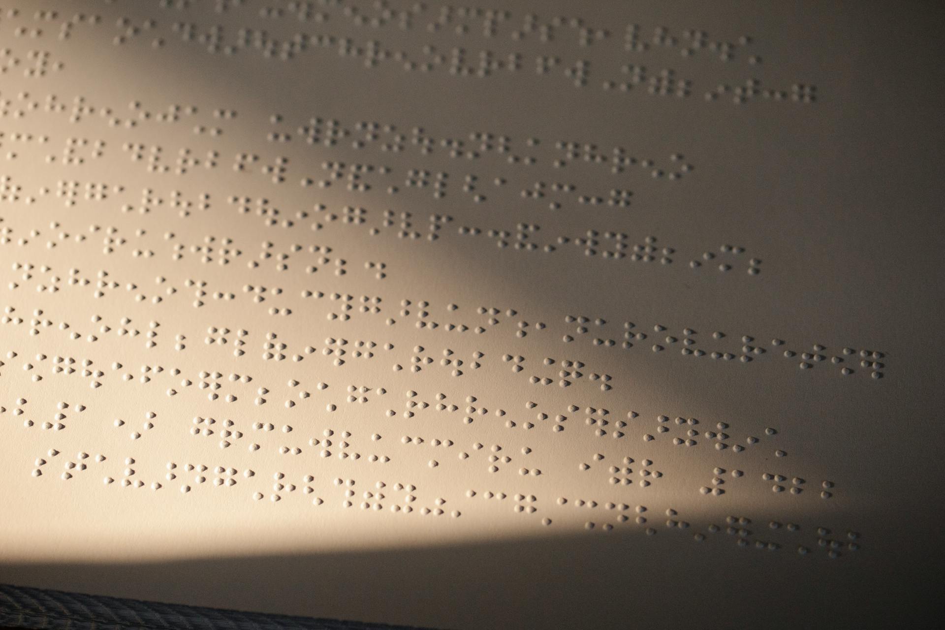 Close-up of Braille text embossed on paper with light and shadow effects.