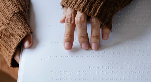 Free Close-up of hands in a knitted sweater reading braille text, emphasizing tactile sensory perception. Stock Photo