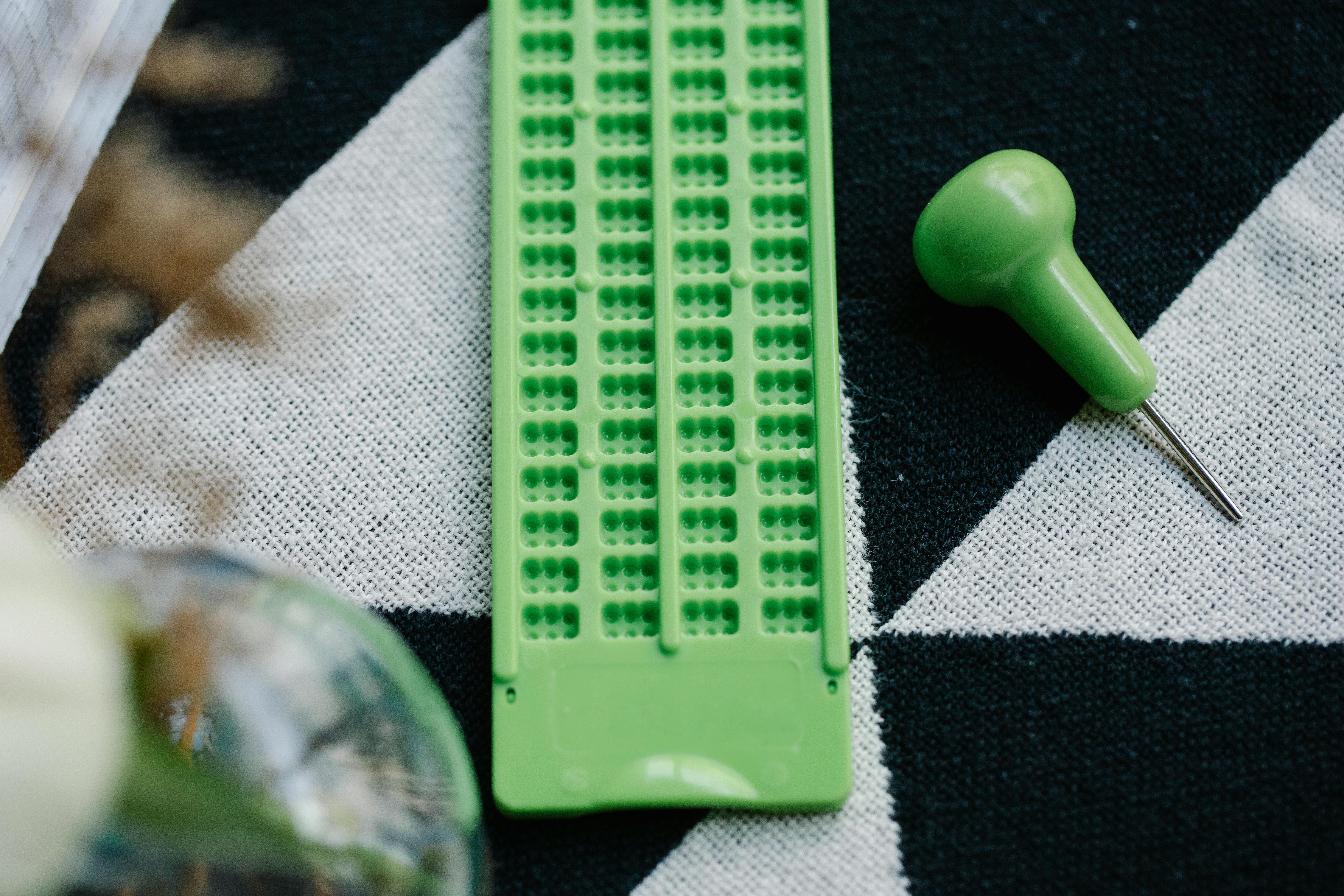 Detailed view of a green planting tool on patterned textile, highlighting gardening essentials.