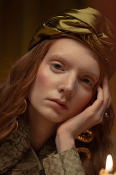 Fashion portrait of a redheaded woman with a glamorous silk headband and dramatic lighting.