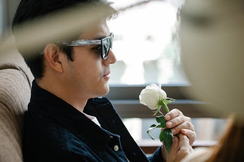 Side View Photo of Man Smelling White Rose