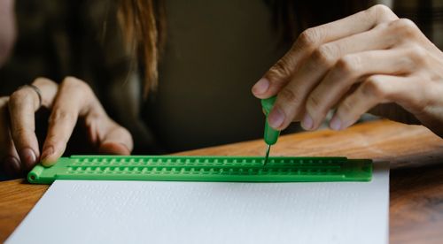 Free Crop anonymous person with vision loss writing braille letter with slate and stylus Stock Photo