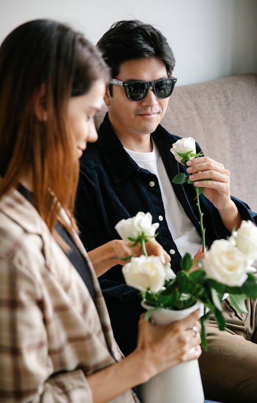 Photo of Woman Arranging Beautiful Roses on White Vase