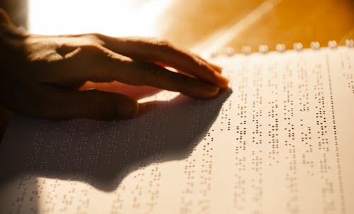 Close-Up Photo of Person Using Book for the Visually Impaired