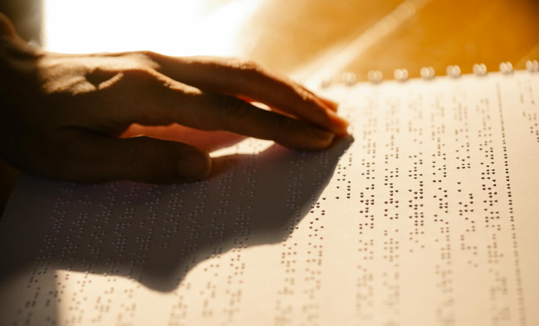 AI Tools to Improve Website Accessibility and Create a Better User Experience 2 A close-up shot of a hand reading a Braille book, symbolizing tactile literacy for the visually impaired.