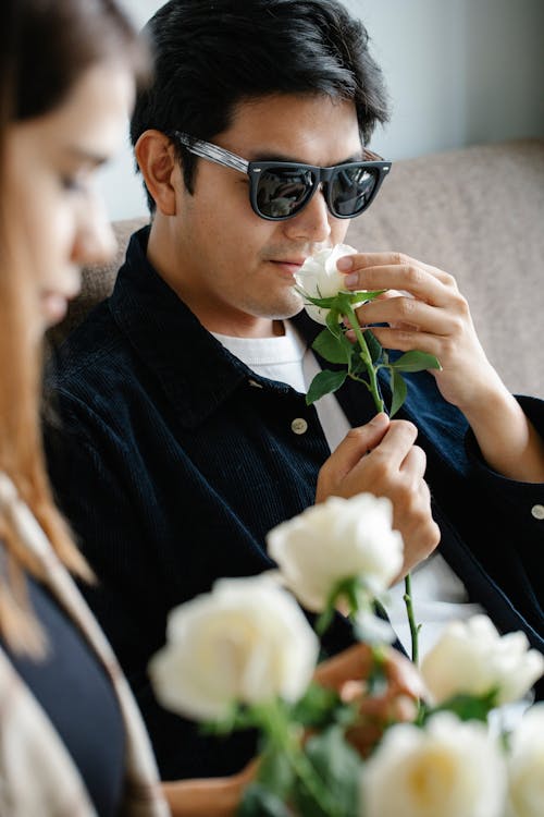 Shallow Focus Photo of Man Smelling White Rose