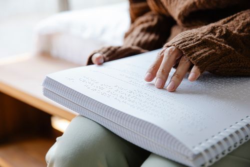 Free Close-up of a person reading a Braille book with focus on hands and texture. Stock Photo