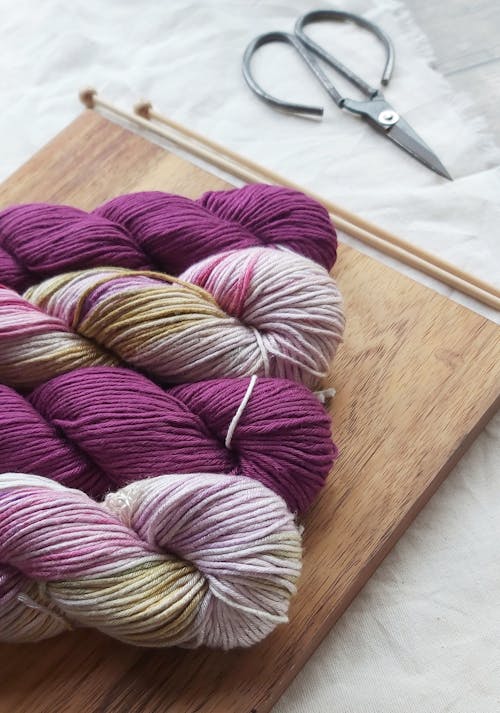 Purple and White Yarn on Brown Wooden Board