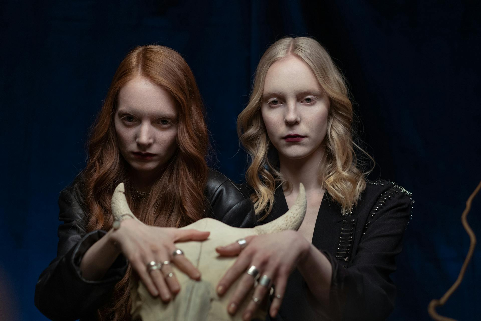 Two Women with Rings in Black Jackets Touching Bull Skull