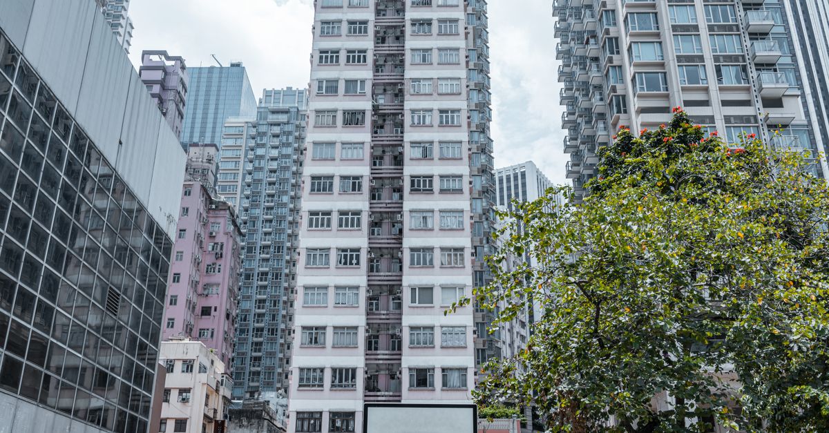 Modern apartment buildings surround a basketball court in a cityscape setting.