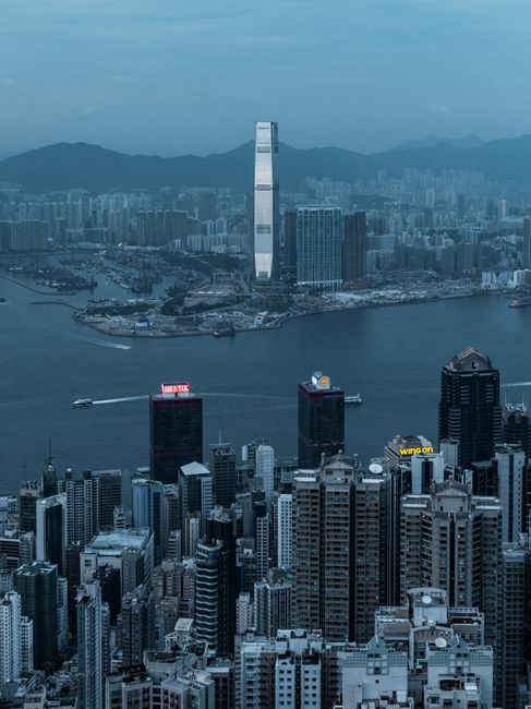 Aerial view of Hong Kong cityscape showcasing skyscrapers and harbor during dusk.