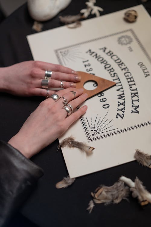 Free Hands of Women Holding an Arrow on a Ouija Board Stock Photo