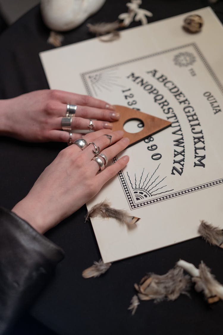 Hands Of Women Holding An Arrow On A Ouija Board