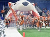 一支美式橄榄球队举着旗帜，热情地进入体育场