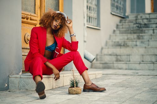 Free Woman Wearing Red Blazer and Pants Sitting on Marble Ground Stock Photo