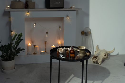 Bottles on Black Round Table in the Room with Fireplace and Cow Skull