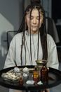 Woman with Braids Sitting in Front of Black Round Table with Mystical Objects