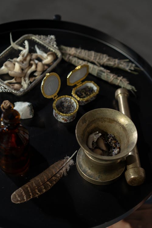 Free Brass Mortar and Pestle and Witchcraft Materials on a Round Table Stock Photo