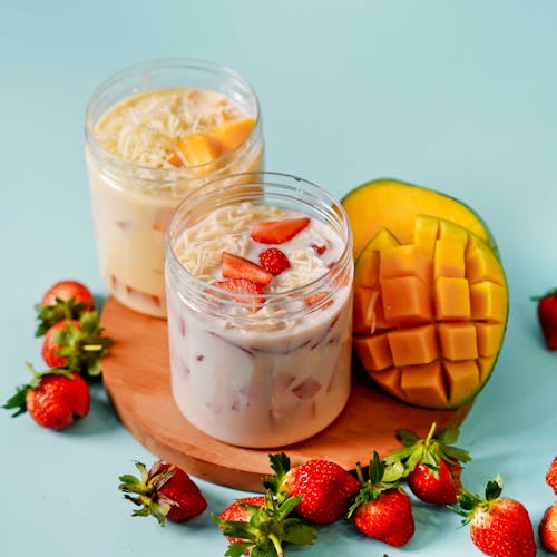 Fruit Salad with Yoghurt in Plastic Jars on Chopping Board Beside Mango