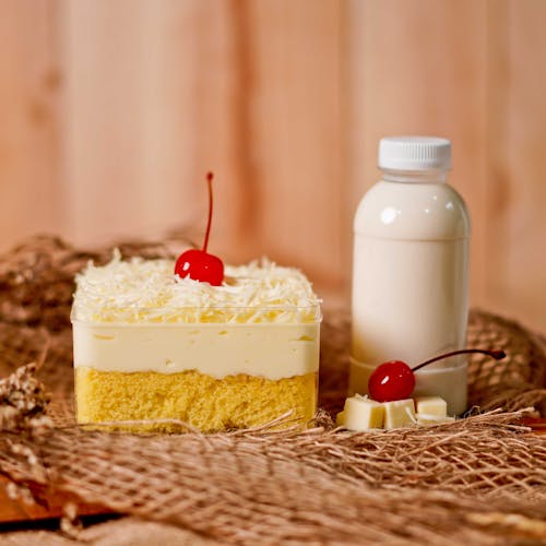 Free Cake With White Cream and Cherry on Top Beside Milk Bottle Stock Photo