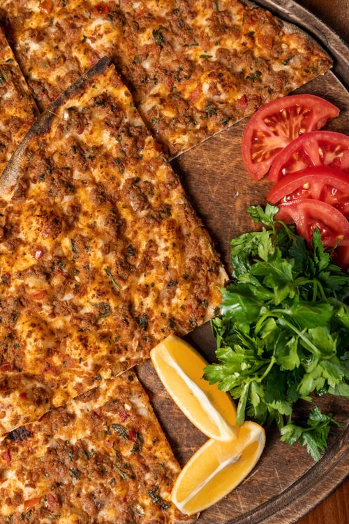 Free Top view of sliced lahmacun with tomatoes, parsley, and lemon on a wooden board. Stock Photo