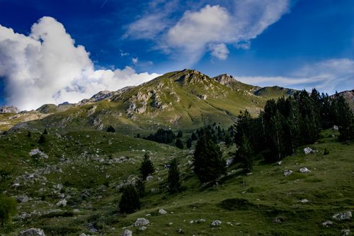Free Captivating view of a lush green mountain landscape with dramatic clouds and blue sky. Stock Photo
