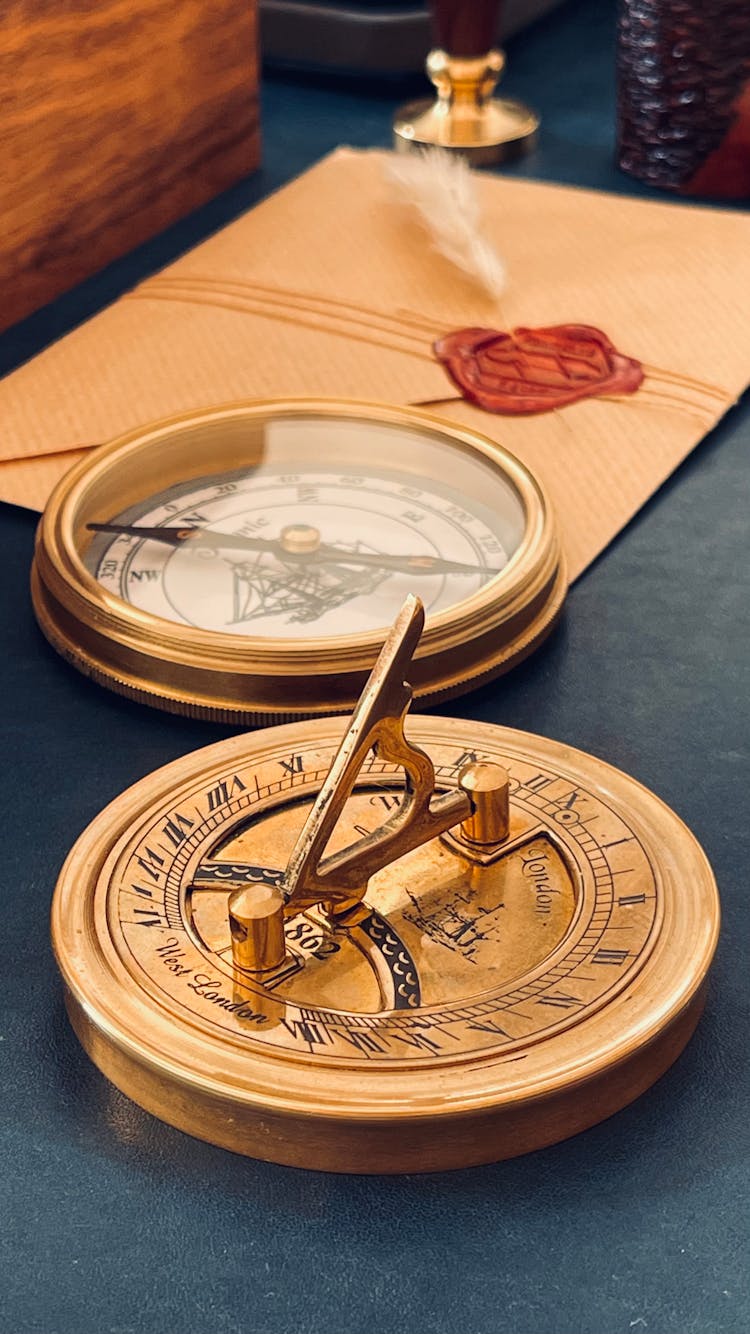 Golden Sundial And Compass On Gray Table