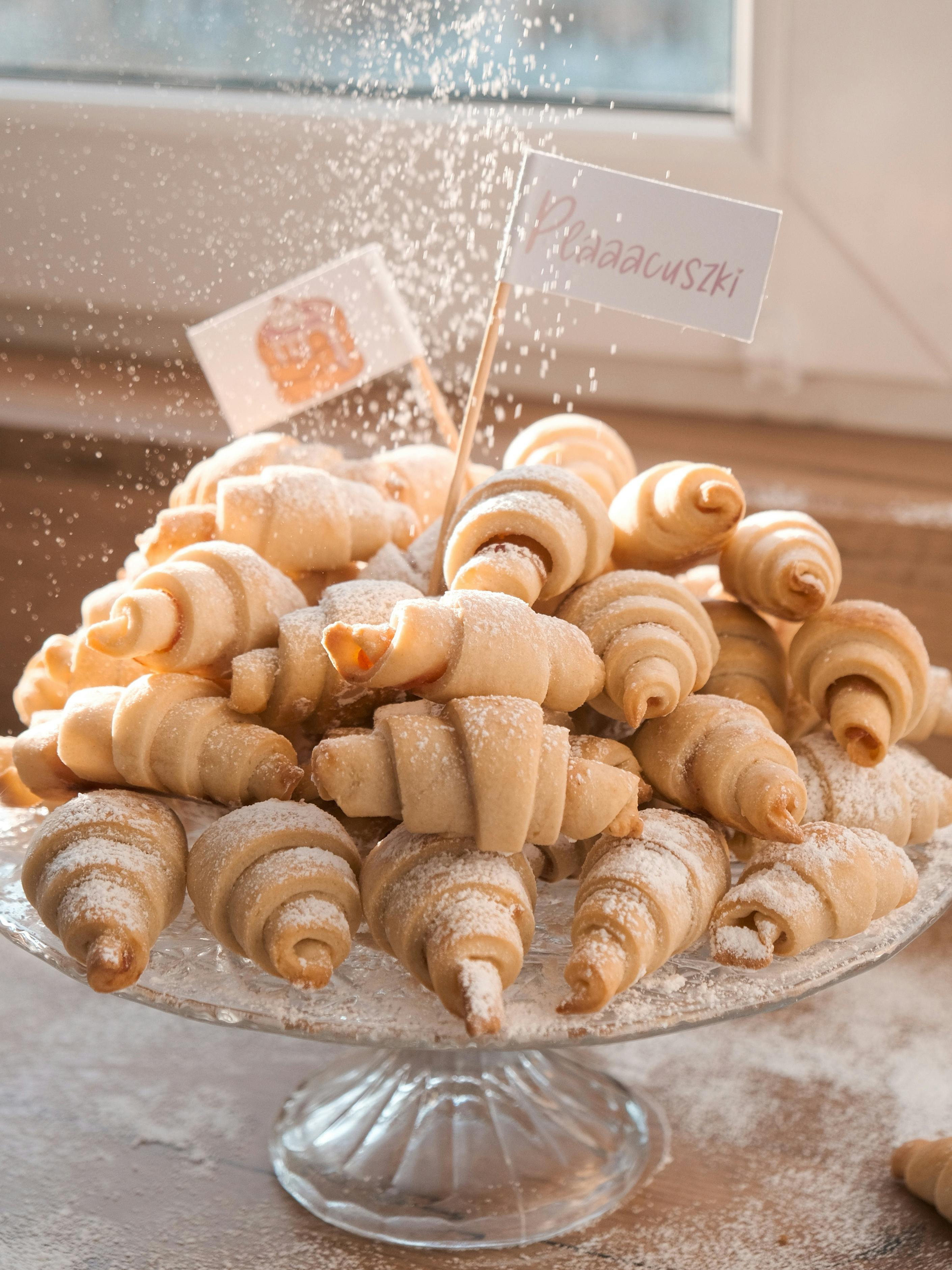 A delectable plate of sweet croissants dusted with powdered sugar, perfect for breakfast.