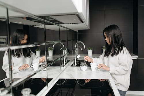 Free Woman in White Sweater Standing beside White Kitchen Counter Stock Photo