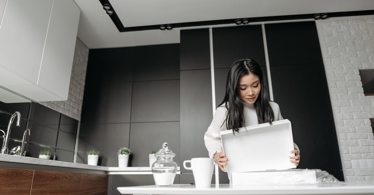 Woman enthusiastically unboxing a package in a modern kitchen setting, showcasing online shopping experience. Local SEO Checklist