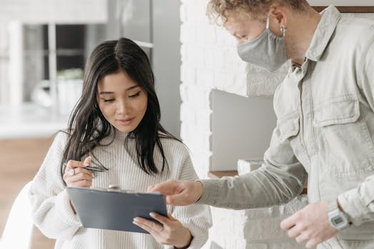 Woman signing delivery form from courier wearing mask. Safe at-home package receipt.