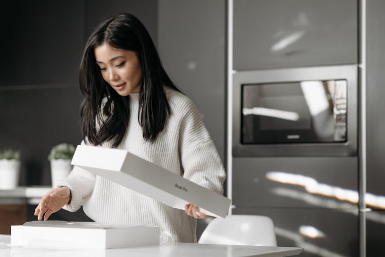 Woman In White Knitted Sweater Unpacking A White Box 