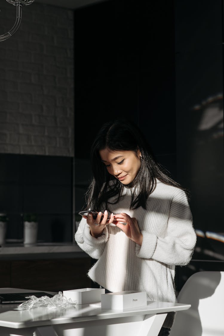 Woman Smiling While Checking Her New Iphone 