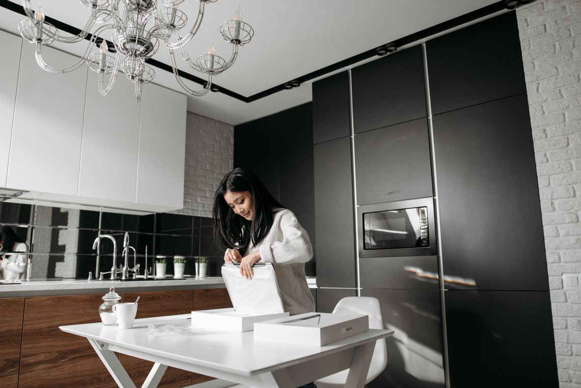 Woman opening a delivered package at a table in a modern kitchen