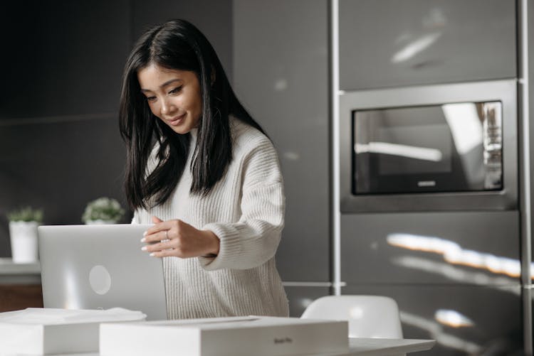 A Woman Smiling While Looking At Her Laptop