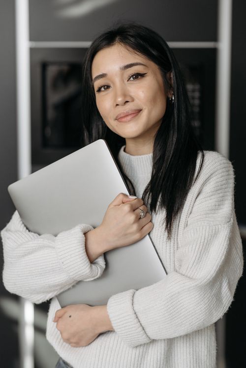 Free Young woman with laptop smiling indoors, showcasing technology and warmth. Stock Photo
