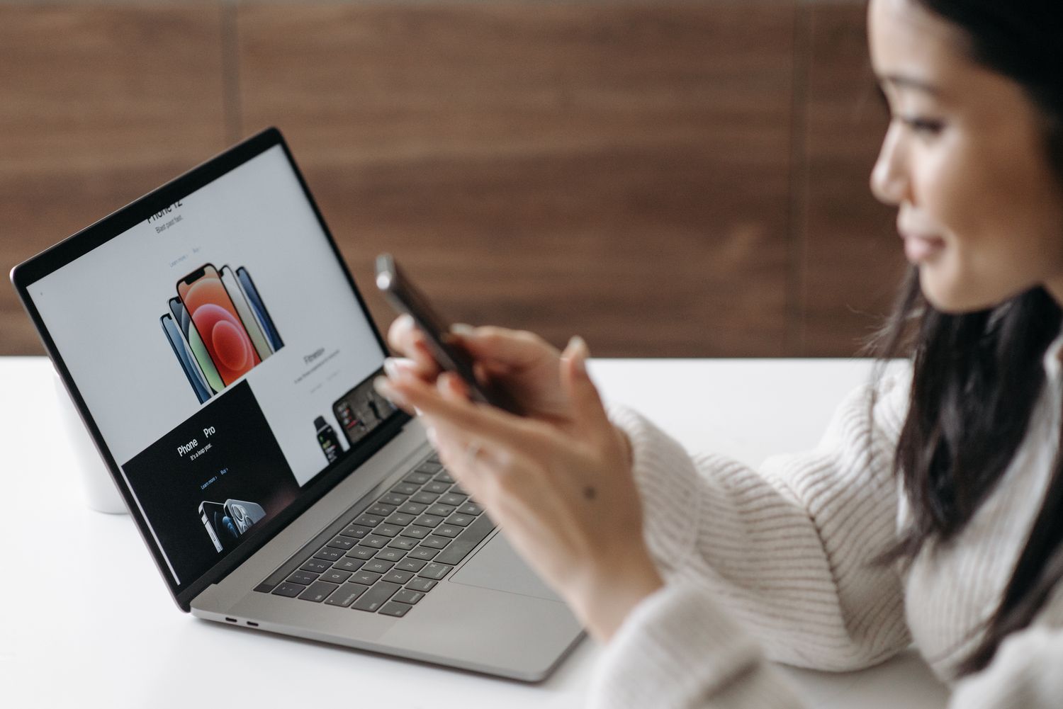 Woman using a smartphone and laptop to browse online shopping options