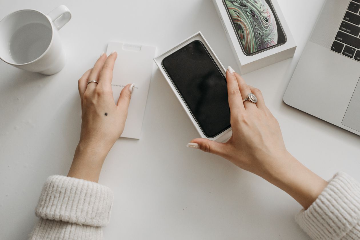 Woman unboxing a new smartphone on a white table