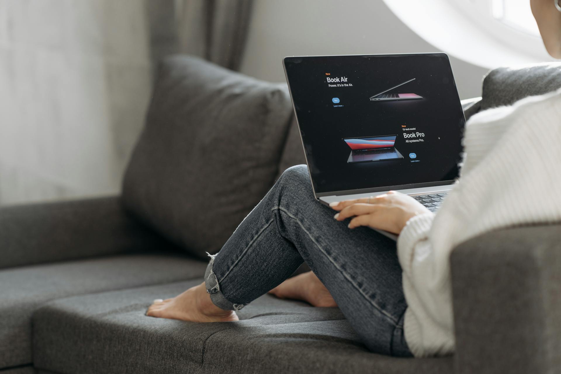 Woman Sitting on the Couch and Choosing Laptop Online