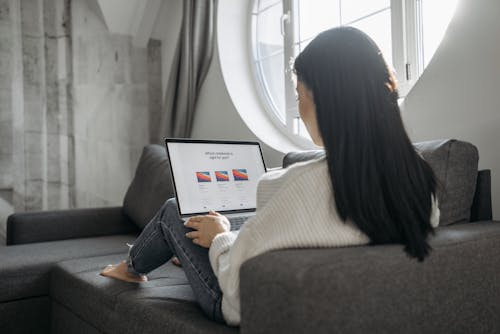 Woman Using Laptop while Sitting on the Sofa