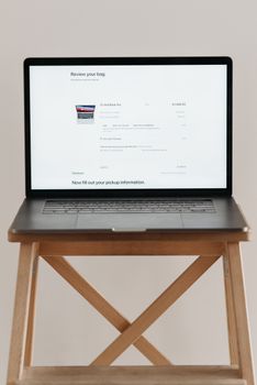 Open laptop displaying checkout screen on a wooden stand, ideal for e-commerce themes.